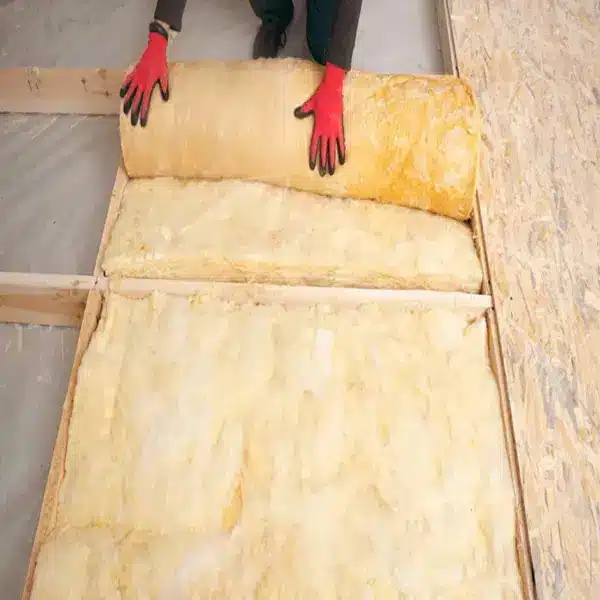 Aerolite glasswool being rolled out between timber ceiling joists